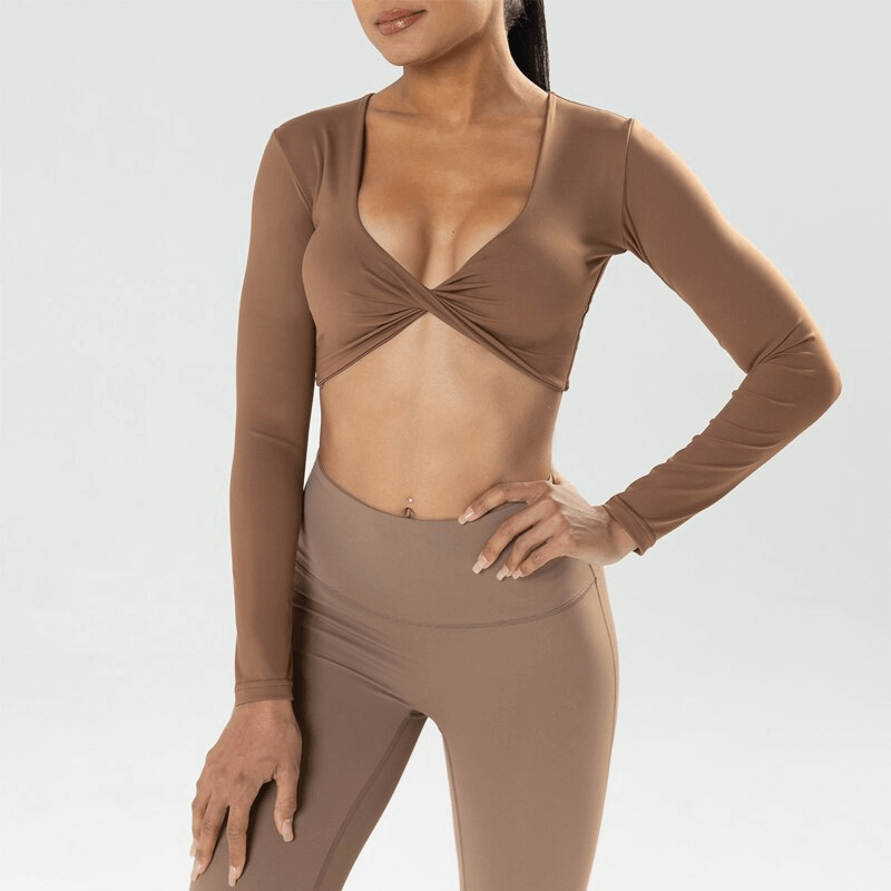 Woman modeling a brown cropped sporty long sleeve top, showing chic design and fit. Perfect for active lifestyle and yoga.
